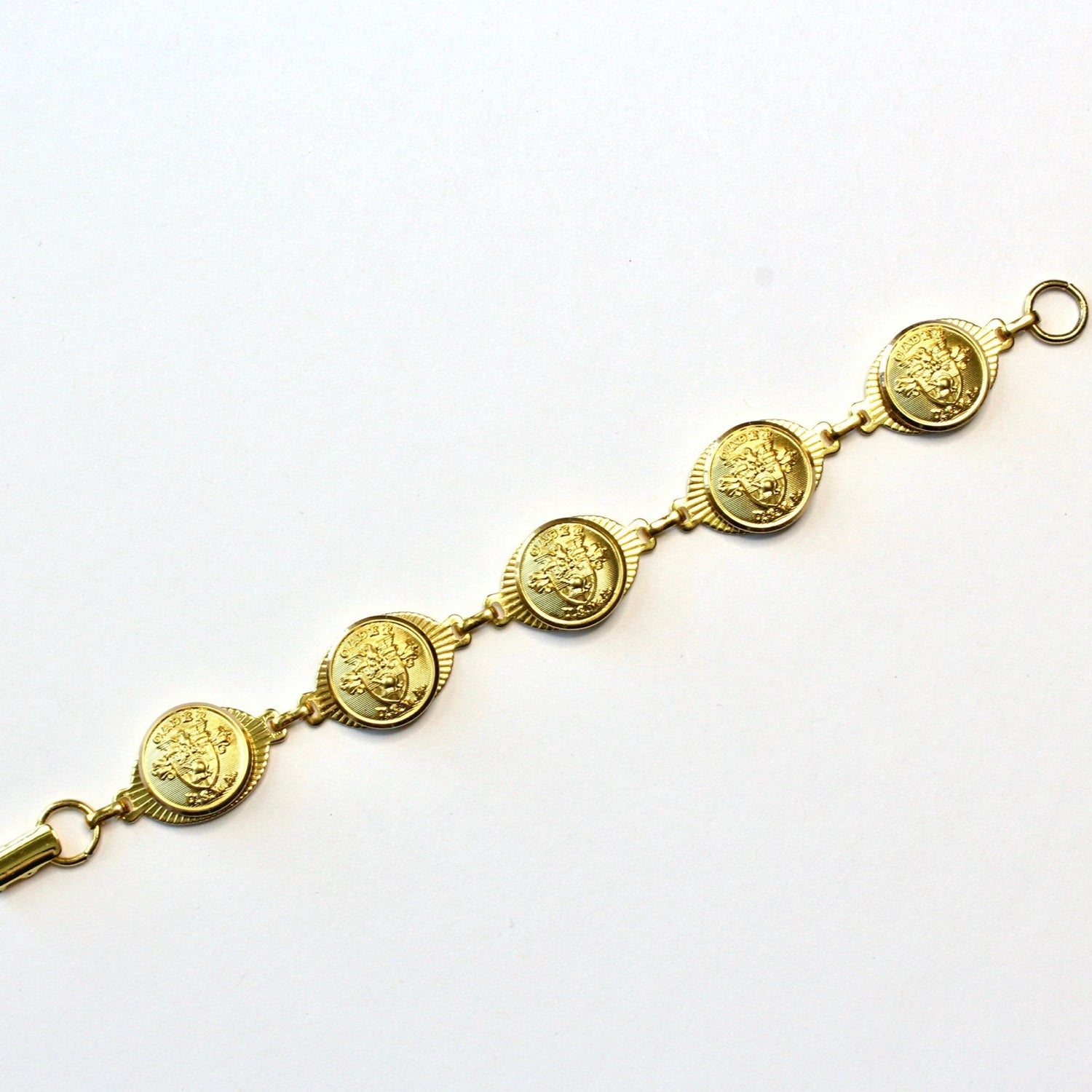 A gold-plated linked bracelet with metallic buttons attached to it, displayed against a white background.