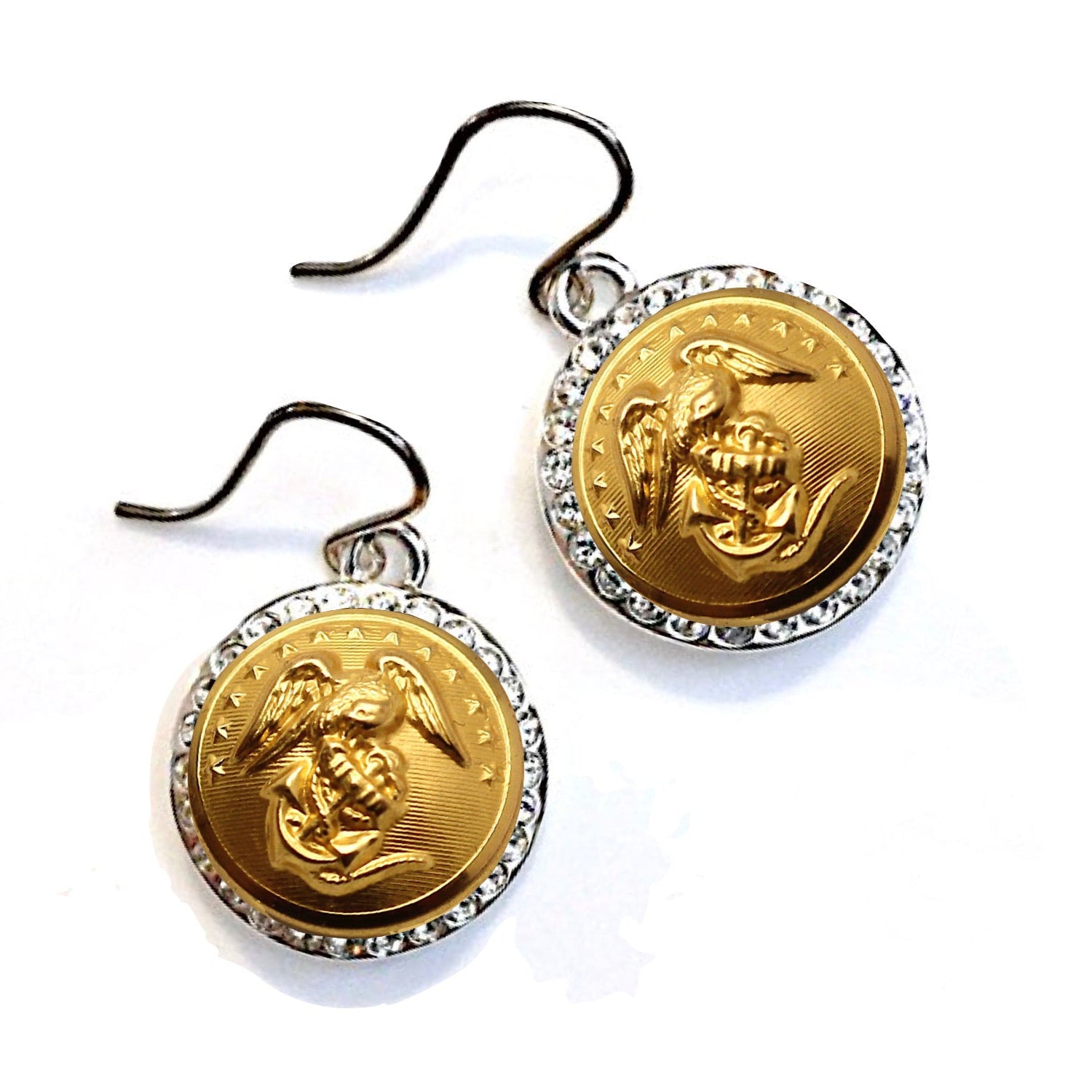 A pair of earrings with gold-colored rhinestone settings and a central military button design.