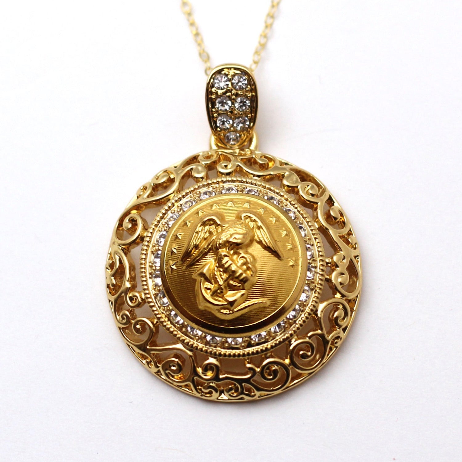 A gold-tone button necklace with a large central crystal and rhinestone pendant, surrounded by smaller clear crystals set in a ornate frame.