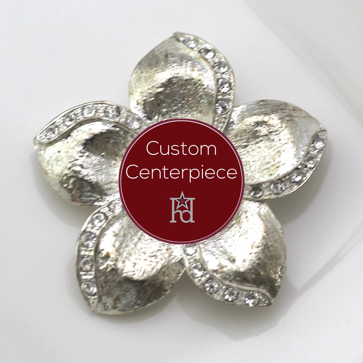 A silver brooch with clear crystals designed in a floral pattern, featuring a custom center piece with the text 'Custom Centerpiece' and the Hope Design Ltd. logo.