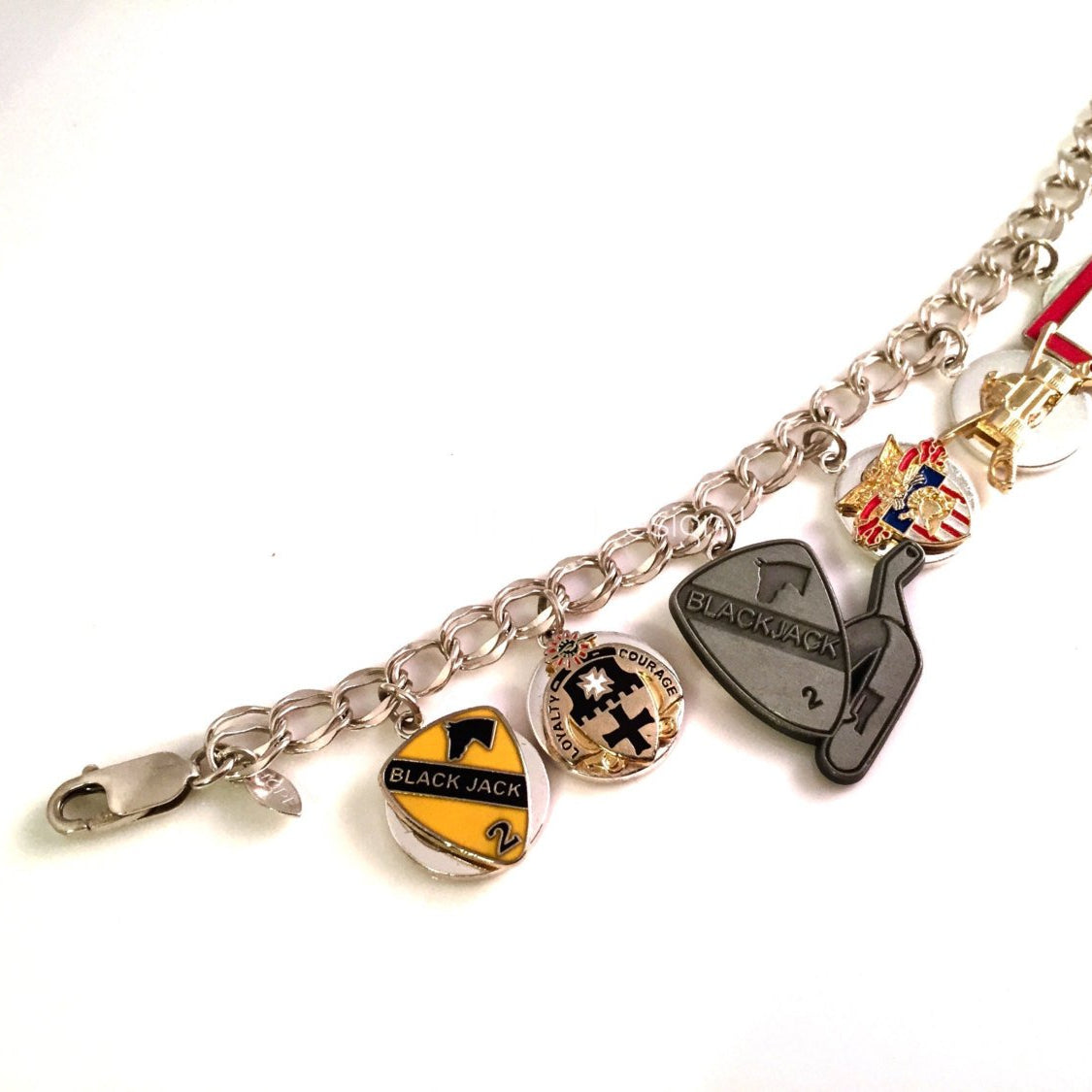 A sterling silver charm bracelet with various charms including a shield, a key, and a football, interspersed with unit pins.