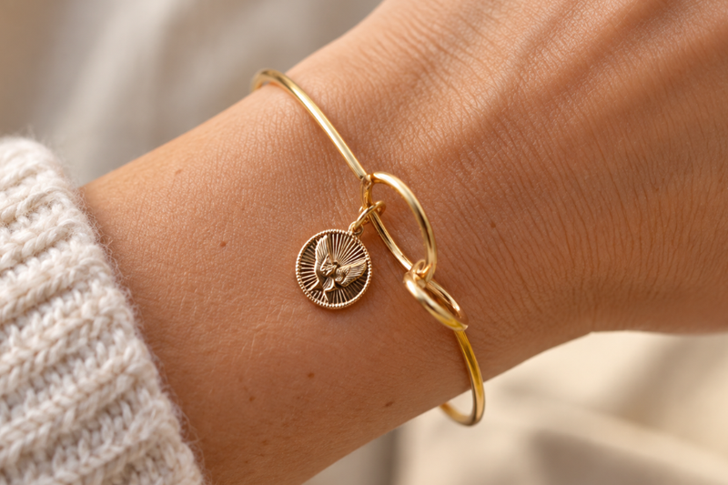 Silver memory wire bracelet with a stamped dandelion charm and pearl charm on a white background