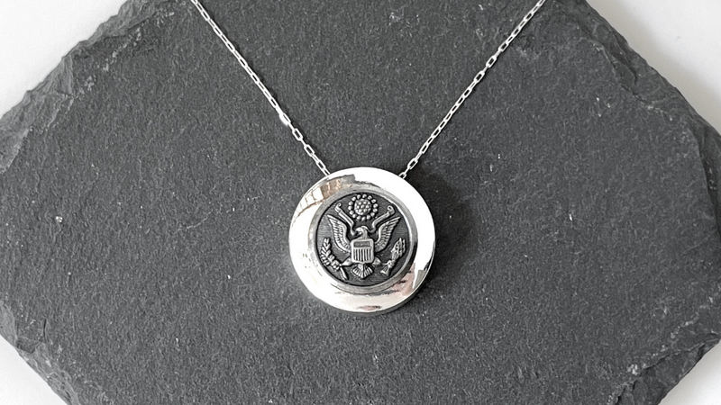 Silver setting with Army button with a silver chain on a slate background