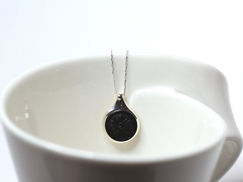 Vintage Army Button on a silver setting and silver chain on a white cup