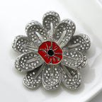 Silver flower-shaped brooch with a red center on a white background