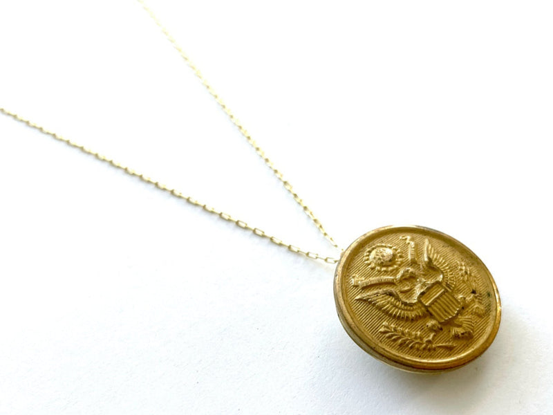 Gold necklace with a round pendant on a white background