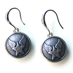 Pair of silver earrings with star and wing design on a white background