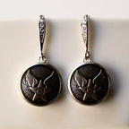 Pair of silver earrings with star and wing design on a light background