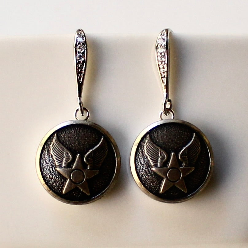Pair of silver earrings with star and wing design on a light background