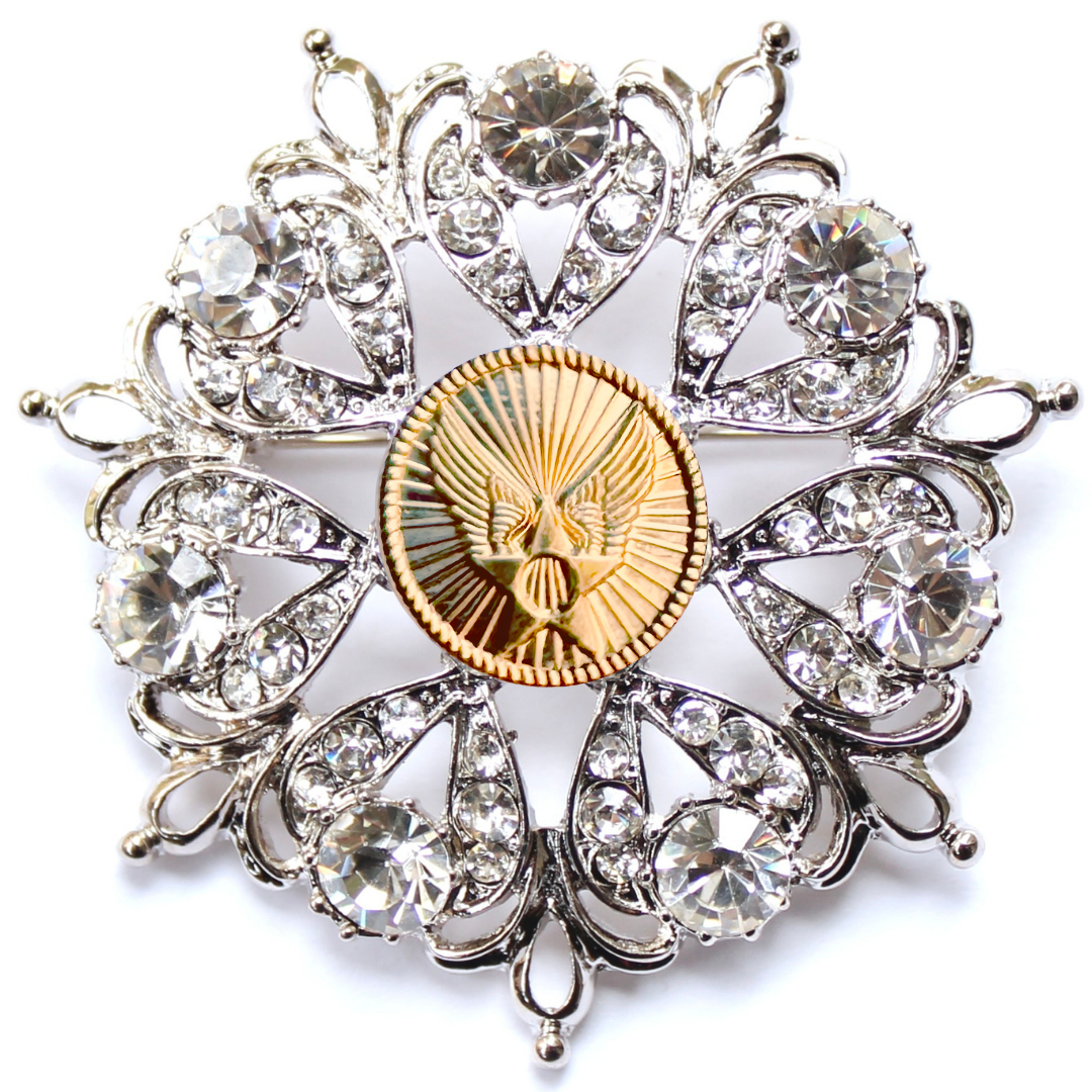 Decorative brooch with crystal-like stones and a gold center on a white background