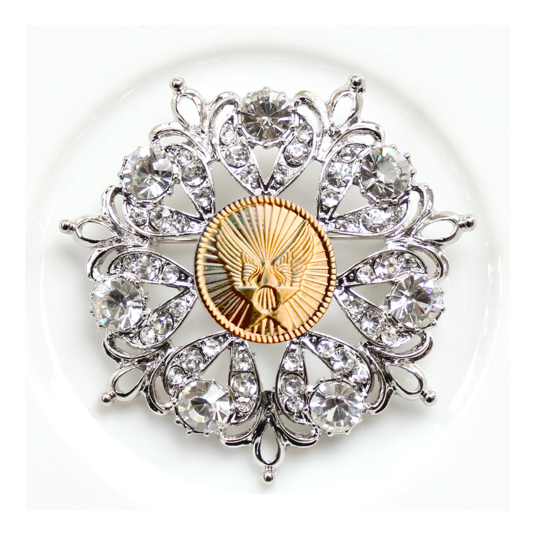 Decorative brooch with crystal elements and a gold center on a white background