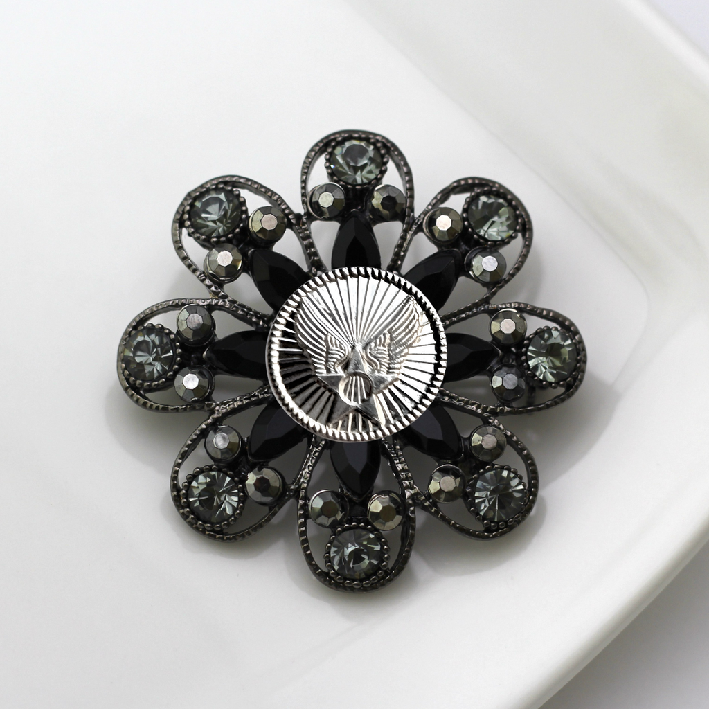 Decorative brooch with black gemstones and silver Air Force inspired centerpiece on a white background