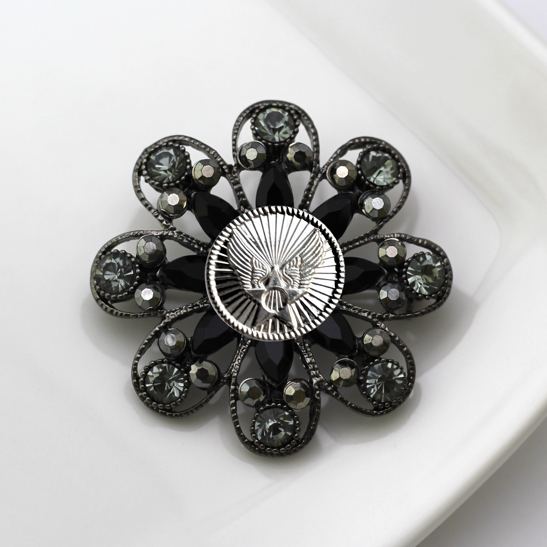 Decorative brooch with black gemstones and silver Air Force inspired centerpiece on a white background
