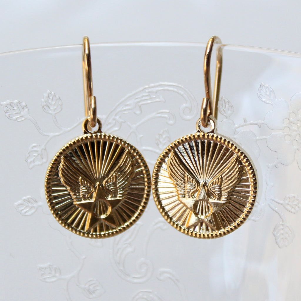 Gold earrings with eagle design on a white background