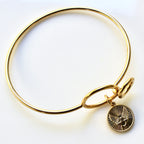 Gold bracelet with a round charm on a white background