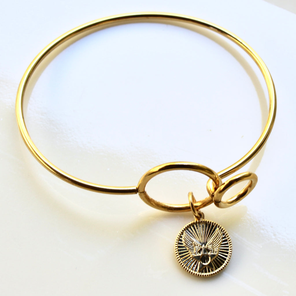 Gold bracelet with a charm on a white background