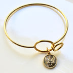 Gold bracelet with a charm on a white background