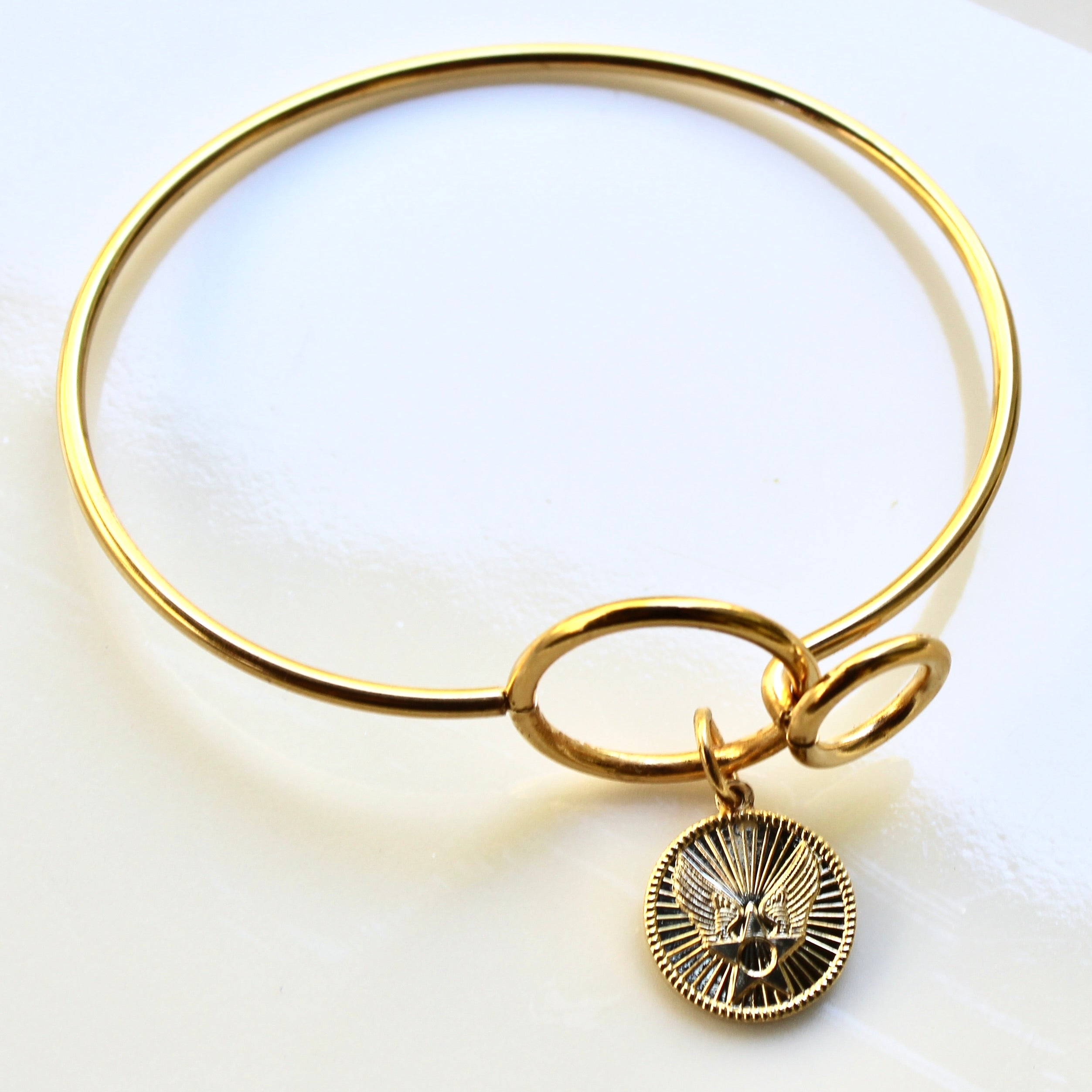 Gold bracelet with a charm on a white background