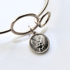 Silver bracelet with a round pendant on a white background