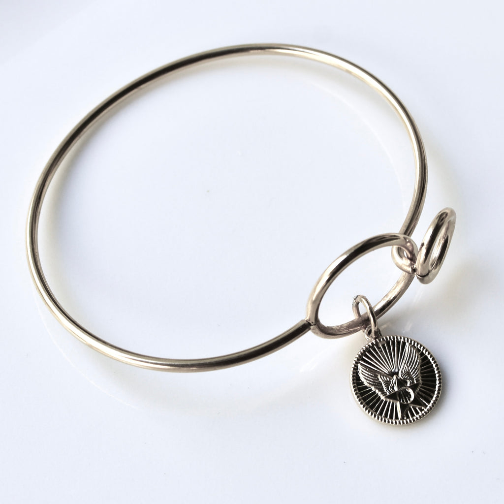 Silver bangle with a circular charm on a white background