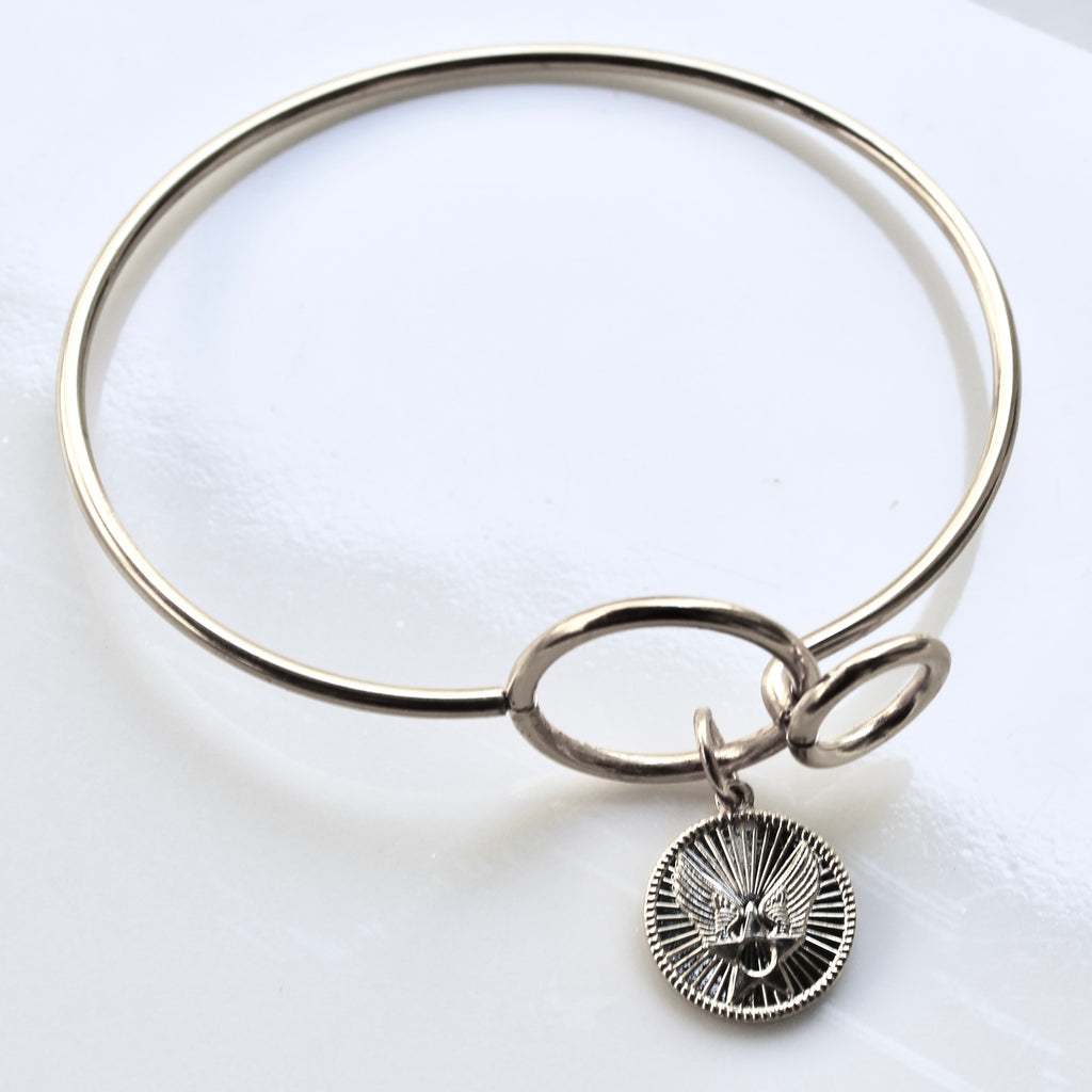 Silver bangle with a round pendant on a white background