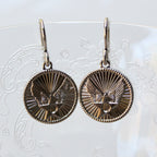 Pair of round earrings with intricate design on a white background
