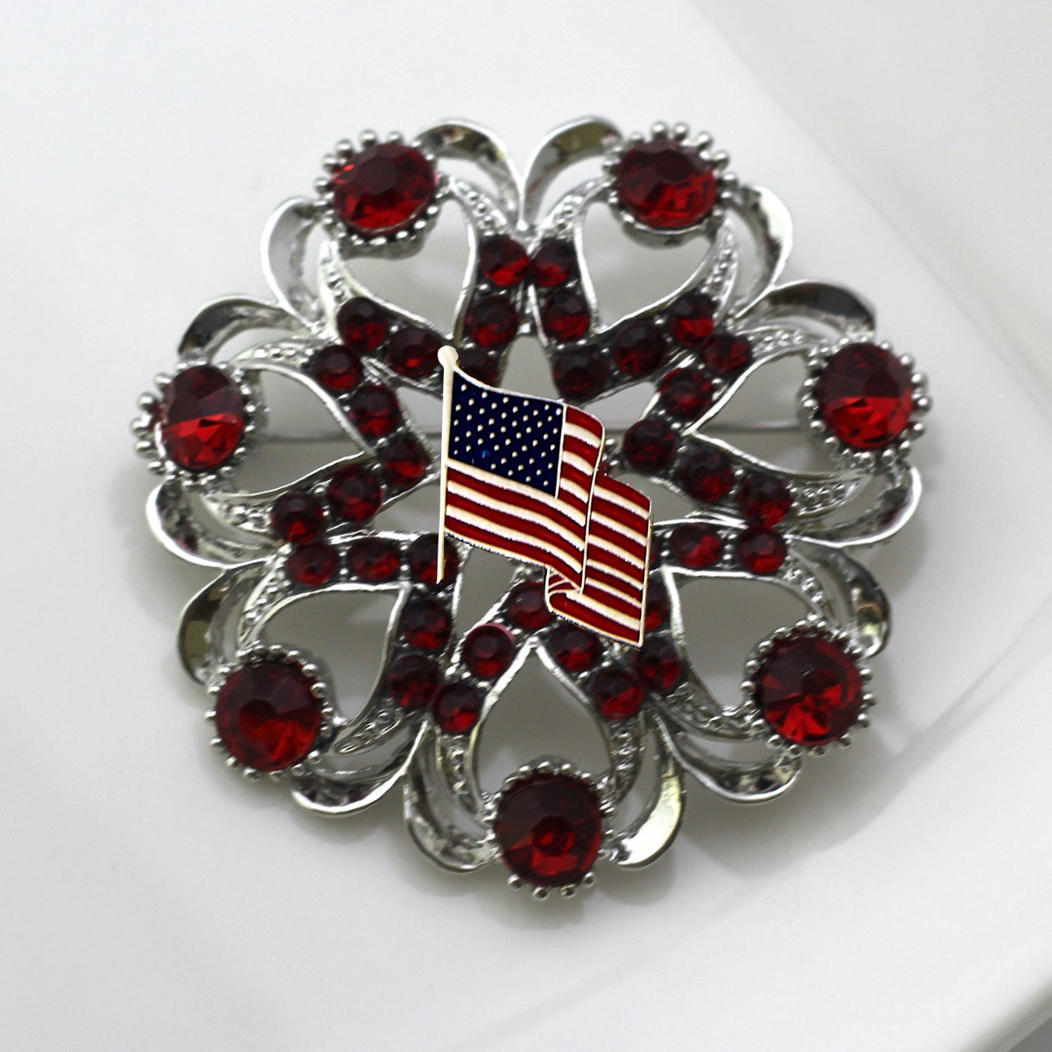 Brooch with American flag and red gemstones on a white background