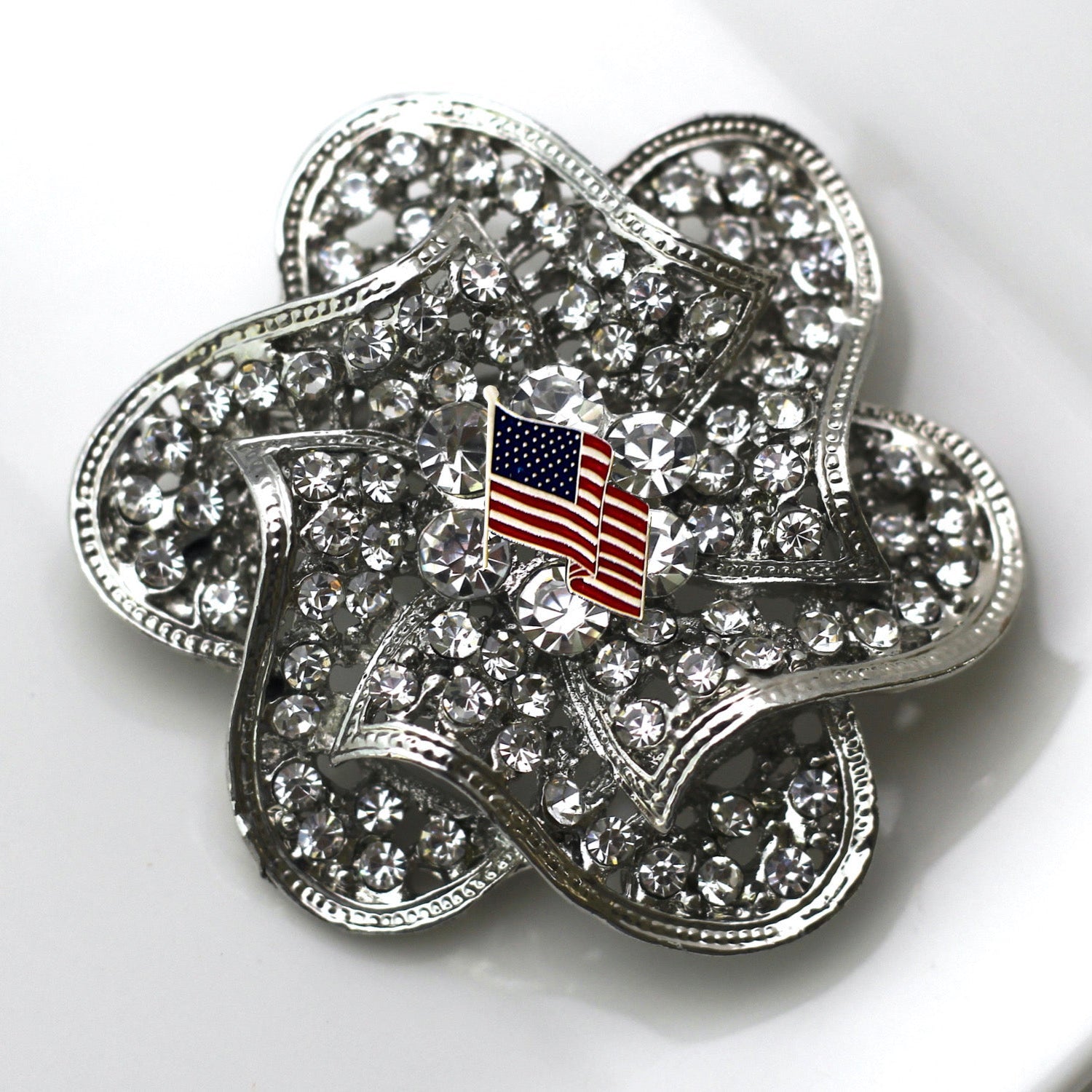Silver four-leaf clover charm with American flag on a white background