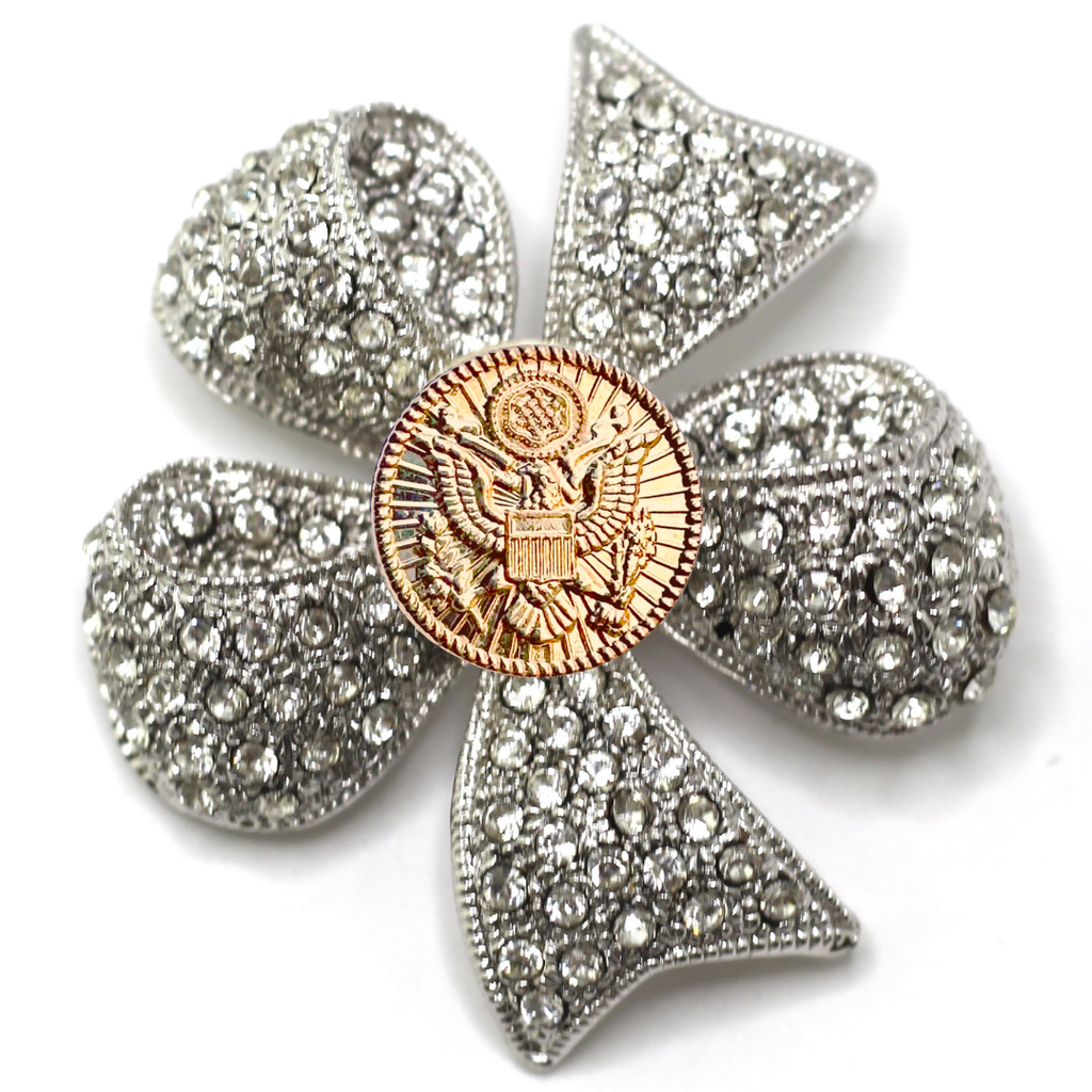 Clover-shaped brooch with rhinestones and a gold center on a white background