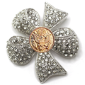 Clover-shaped brooch with rhinestones and a gold center on a white background