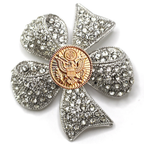 Clover-shaped brooch with rhinestones and a gold center on a white background