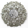 Decorative brooch with intricate design and central Army inspired emblem on a white background