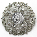 Decorative brooch with intricate design and central Army inspired emblem on a white background