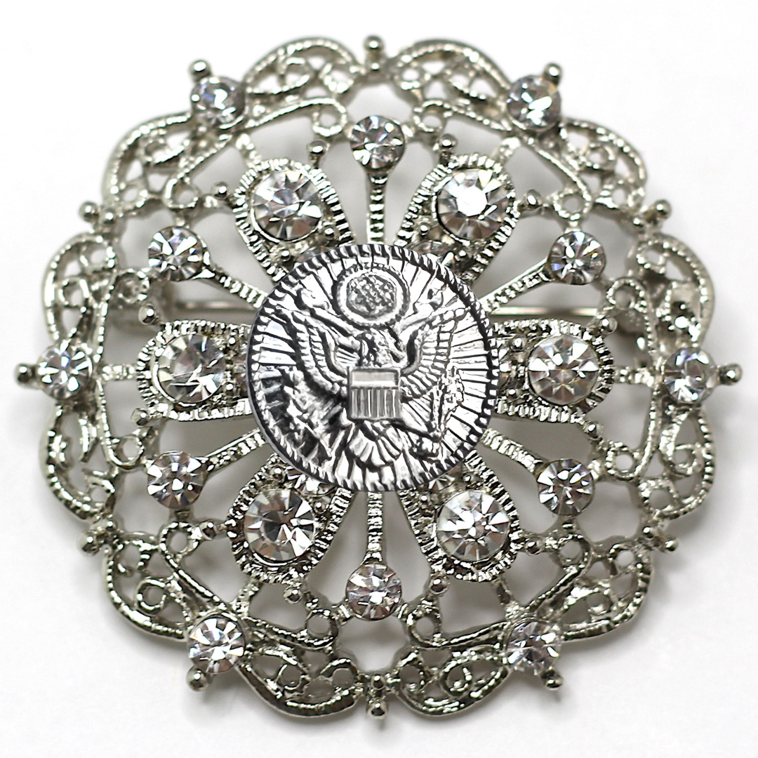 Decorative brooch with intricate design and central Army inspired emblem on a white background