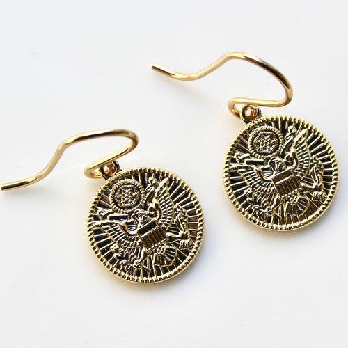 Gold coin-shaped earrings on a white background