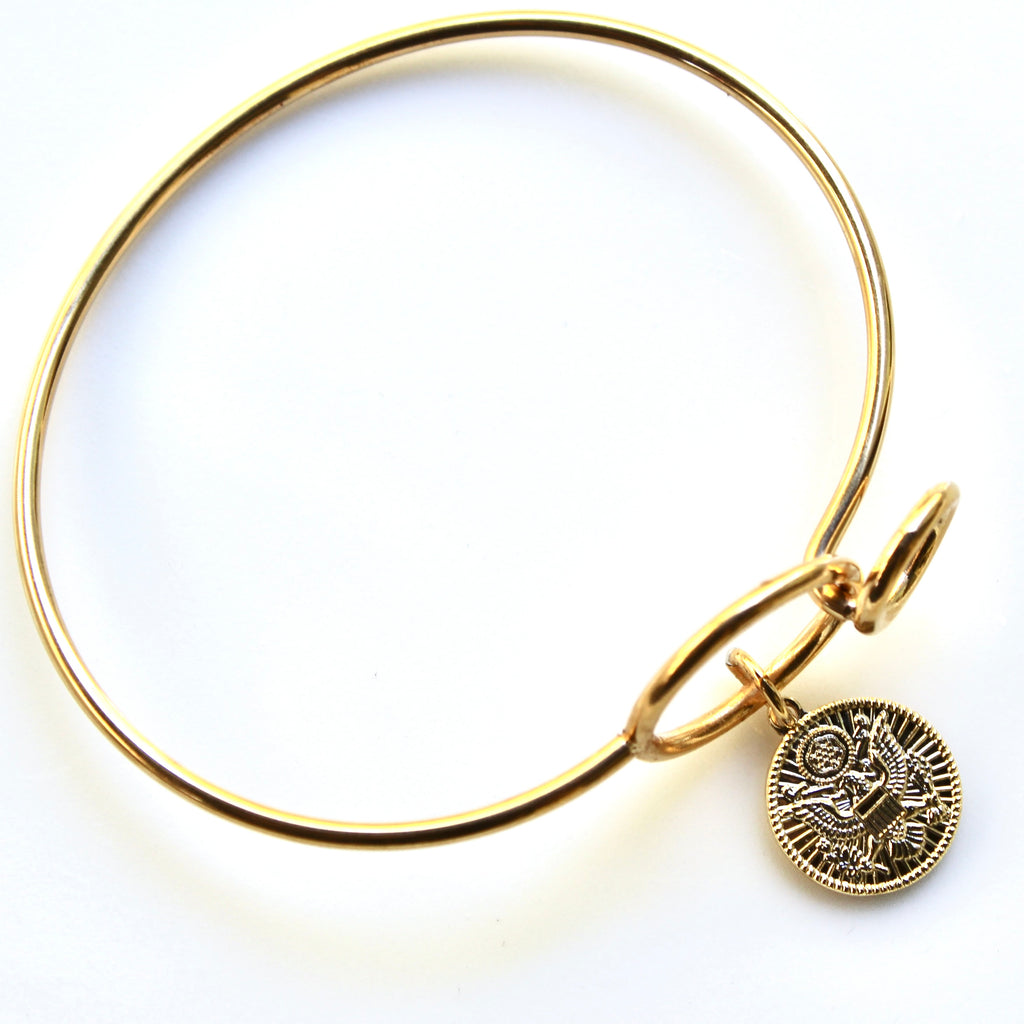 Gold bracelet with a coin charm on a white background