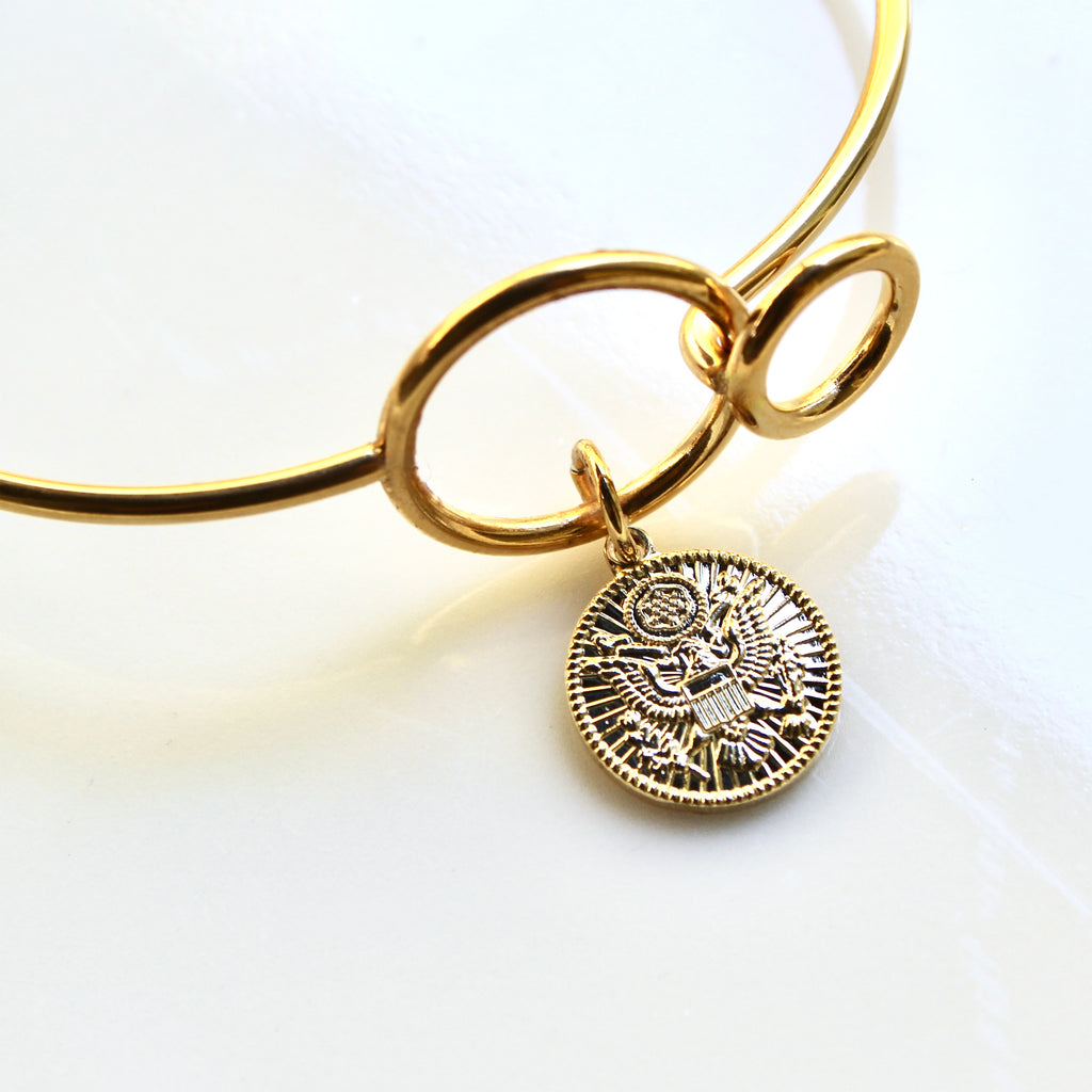 Gold bracelet with a detailed pendant on a white background
