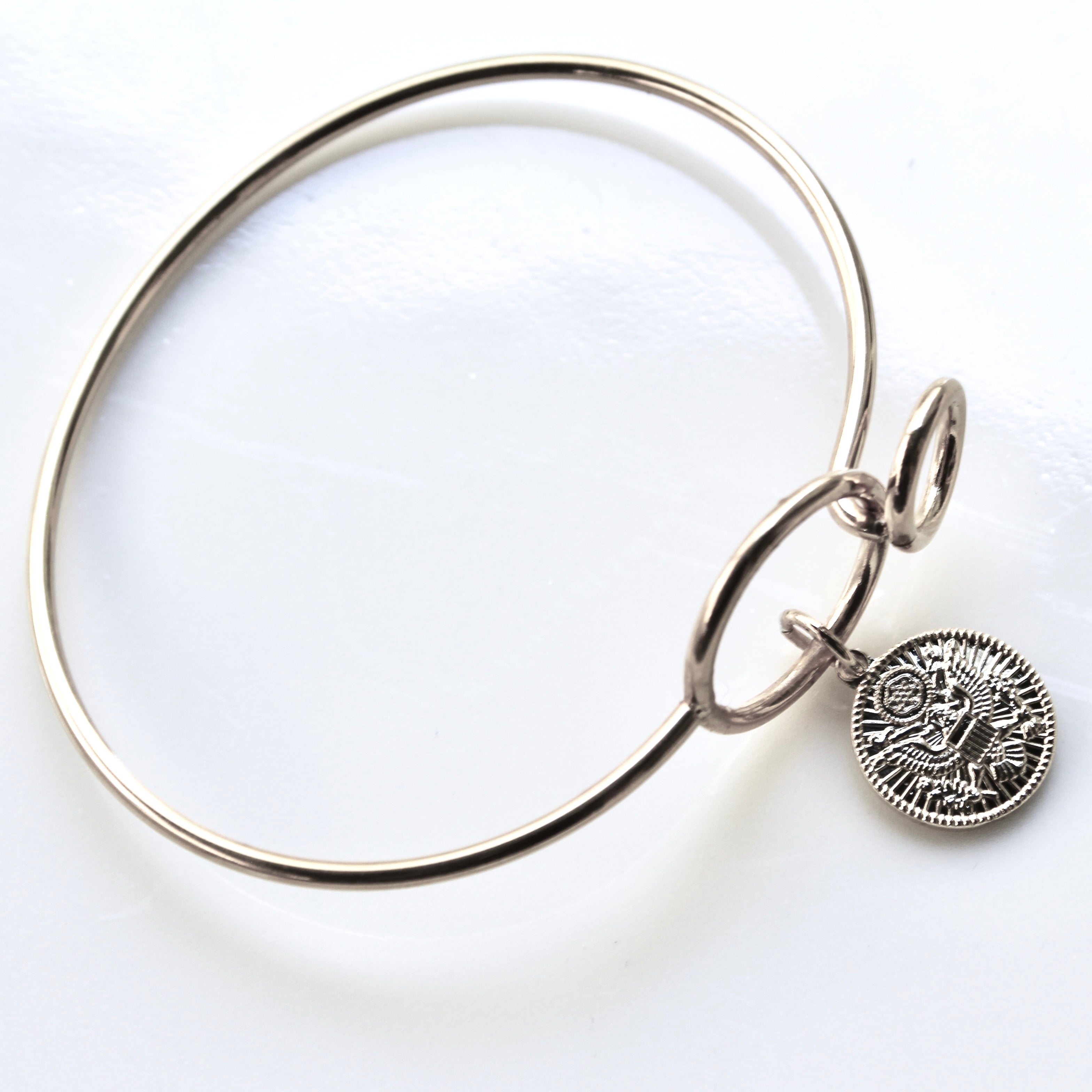 Silver bangle with a round charm on a white background