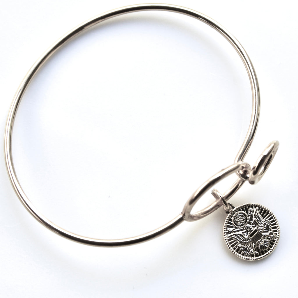 Silver bangle with a round charm on a white background