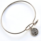 Silver bangle with a round charm on a white background