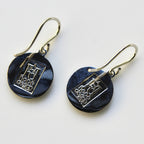 Pair of black earrings with silver designs on a white background