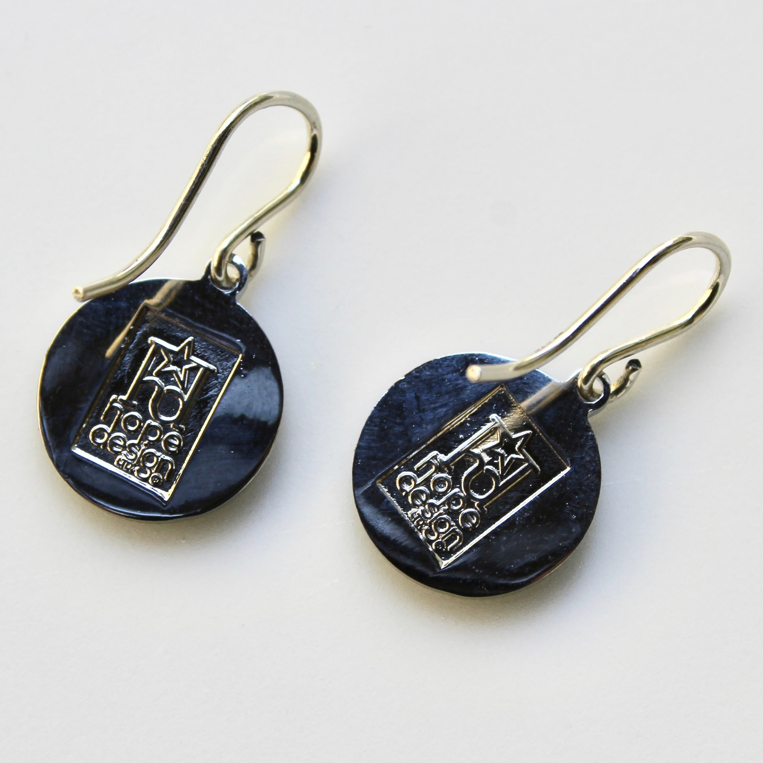 Pair of black earrings with silver designs on a white background