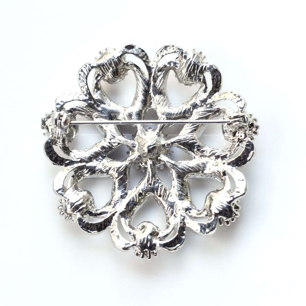Decorative silver brooch on a white background