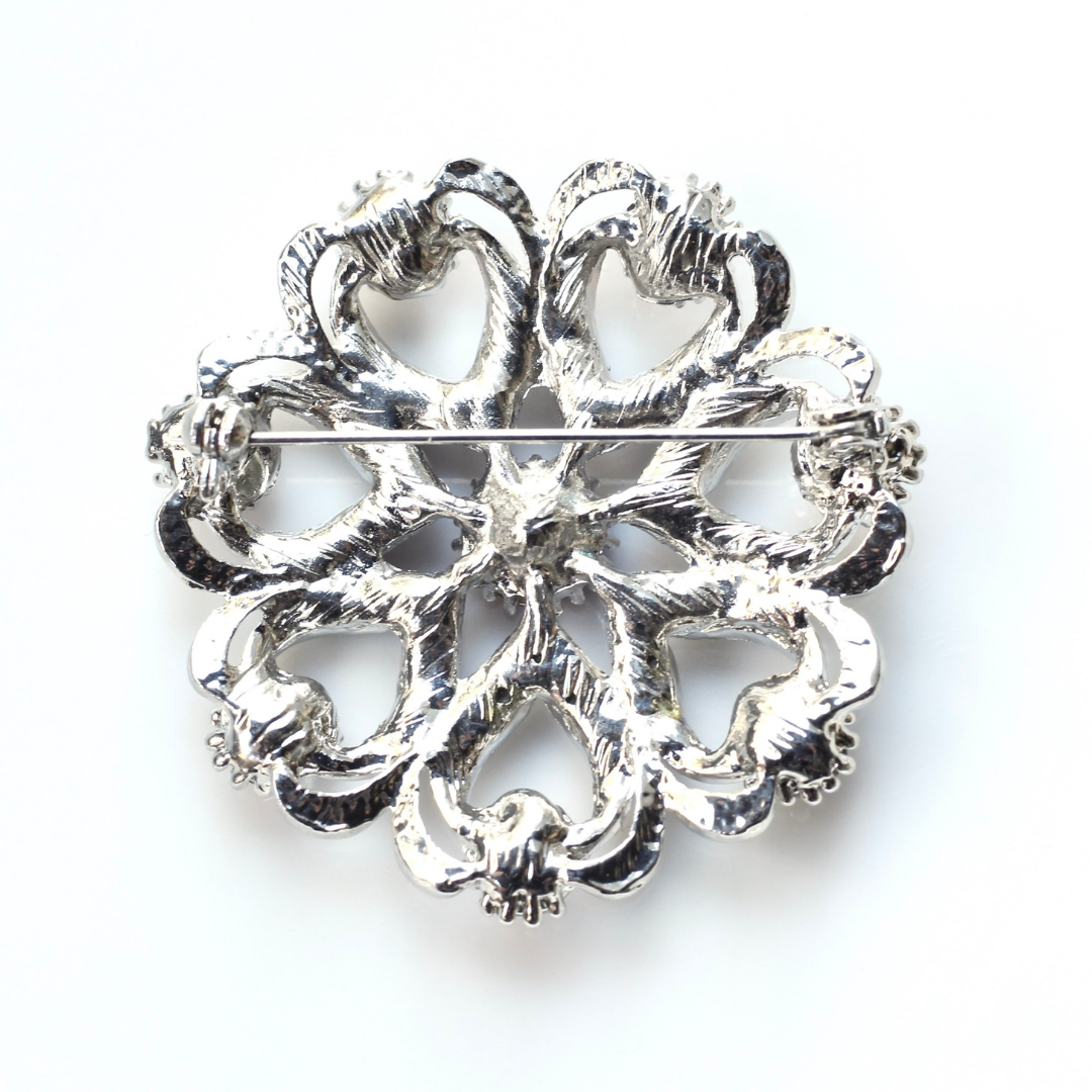 Decorative silver brooch on a white background