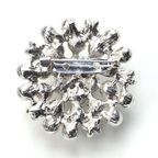 Silver brooch with intricate design on a white background