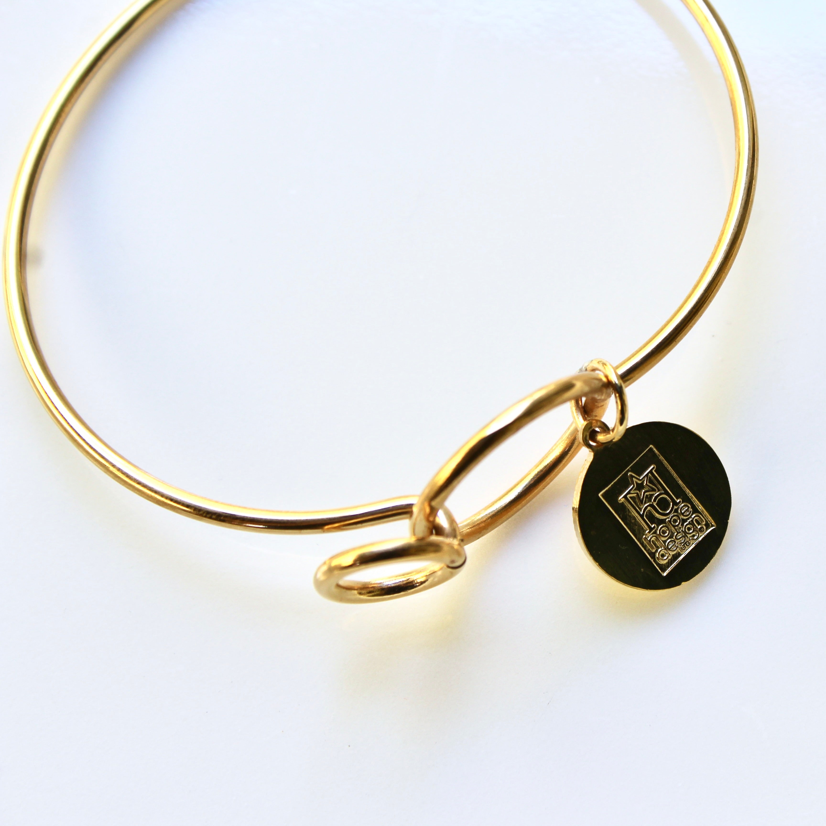 Gold bracelet with a black round charm on a white background