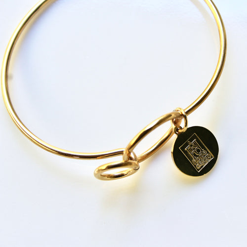 Gold bracelet with a black round charm on a white background