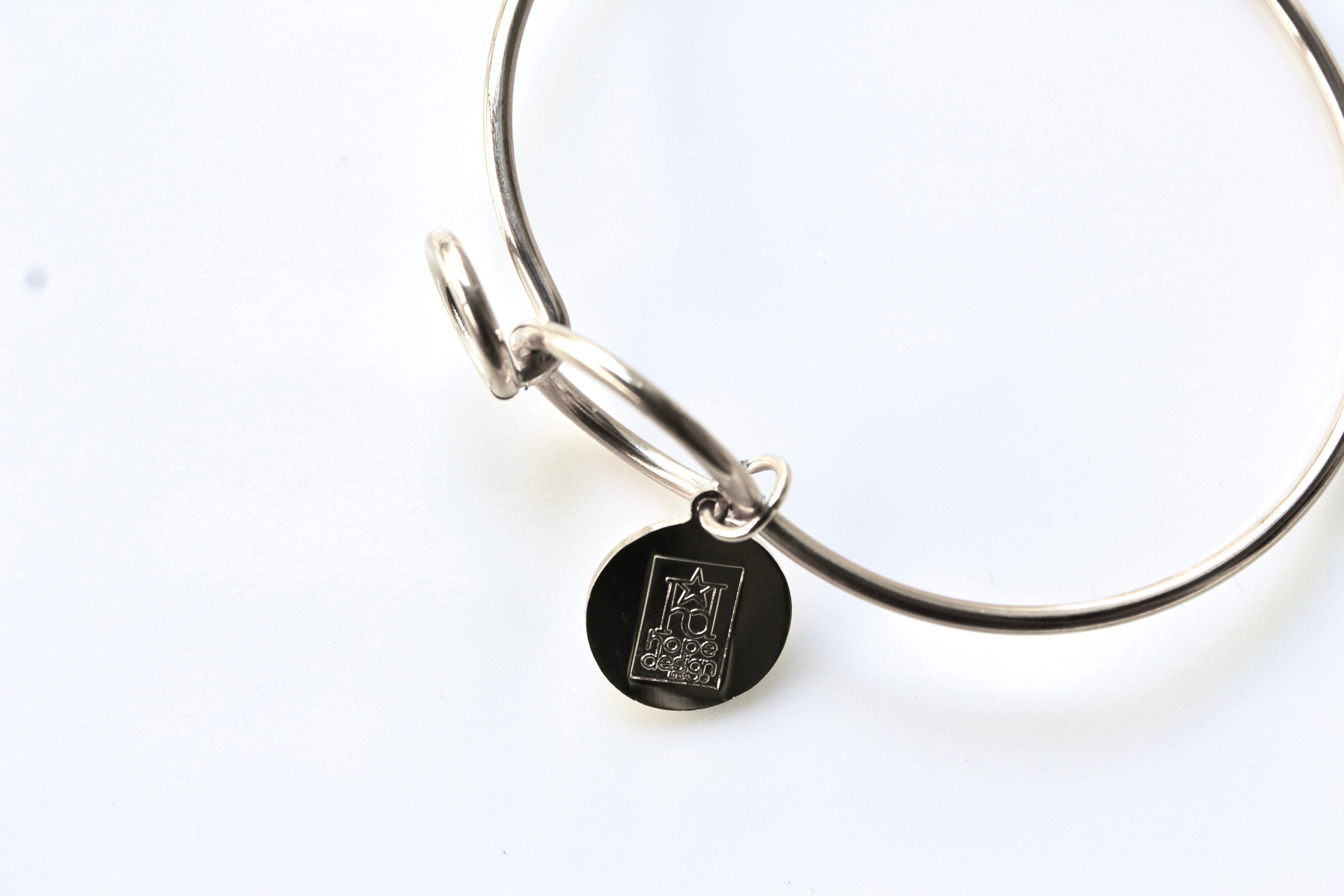 Silver bracelet with a black engraved charm on a white background
