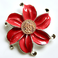 Red flower-shaped brooch with gold center on a white background