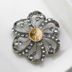 Decorative brooch with crystal-like stones and a gold National Guard center on a white background